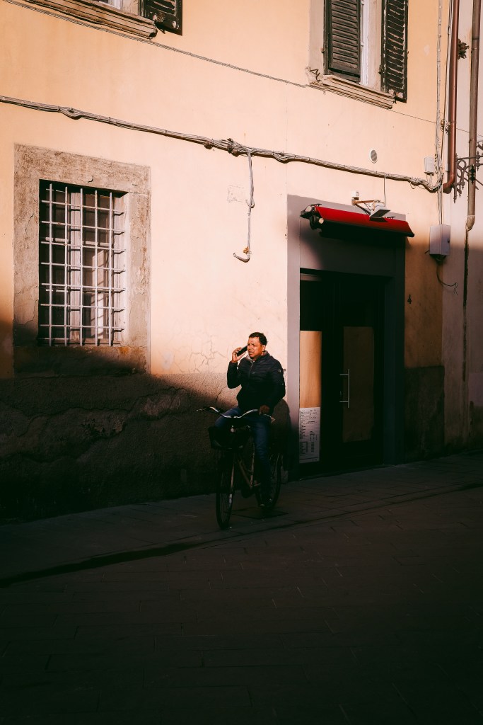 cyclist on the phone in Pisa at golden hour